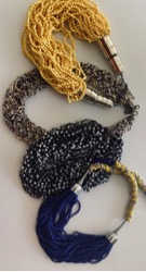 Image of African beads in yellow, tan, black, and navy blue. The beads are looped in circles, four in total.