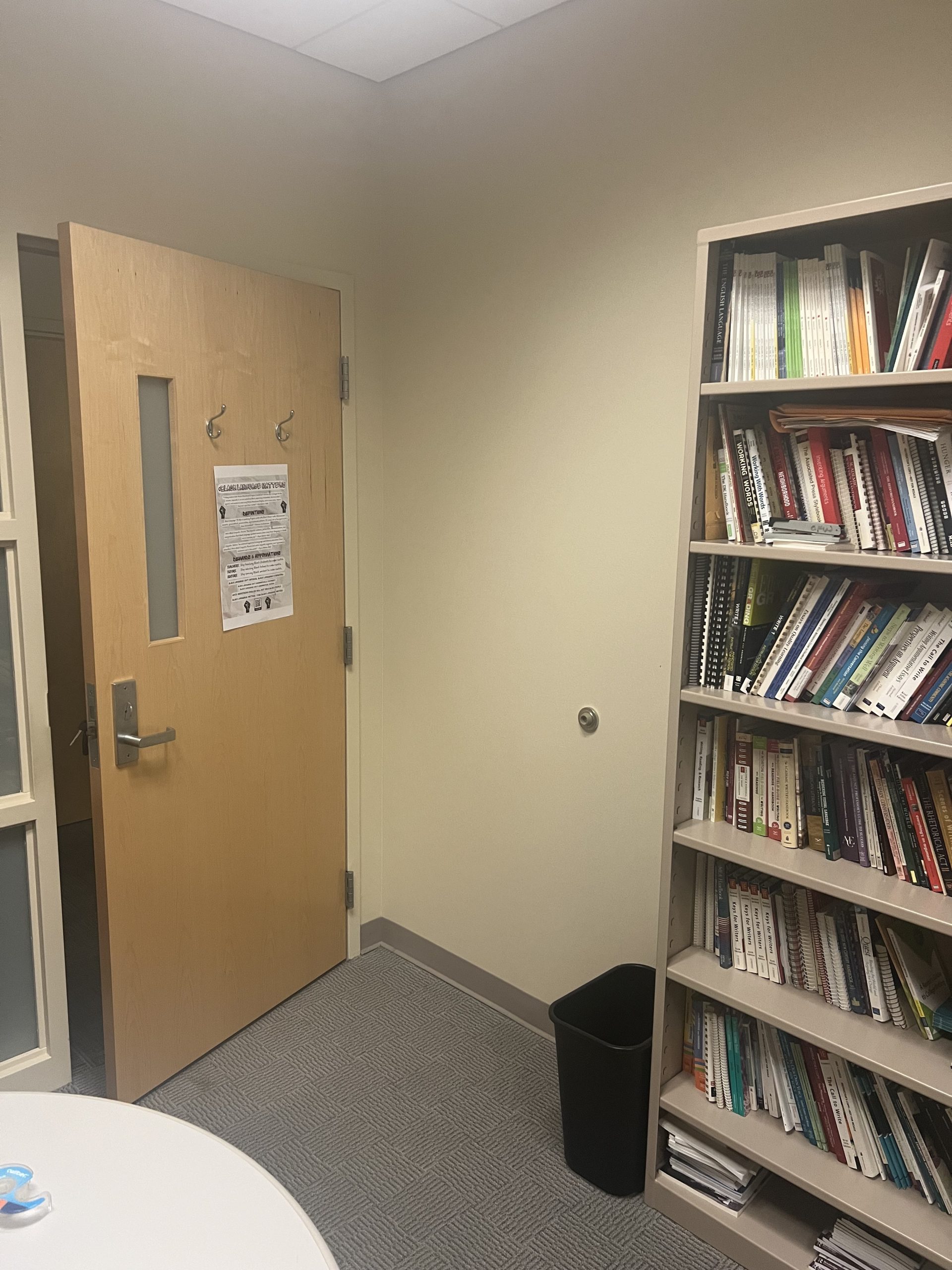 Figure 5: #BlackLanguageMatters poster taped to the inside of an office door. The office includes a bookshelf and table.